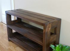 a wooden shelf sitting on top of a hard wood floor next to a planter