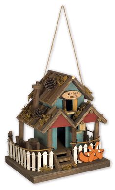 a birdhouse with two pumpkins hanging from it's roof and the door open