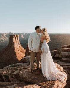 a bride and groom kissing on the edge of a cliff in grand canyon national park