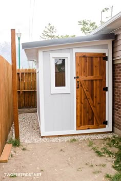 a small white shed with a wooden door