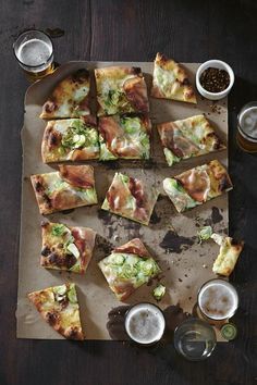 several slices of pizza sitting on top of a cutting board next to cups and sauces