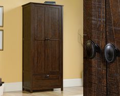 a tall wooden cabinet sitting in the corner of a room