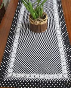 a potted plant sitting on top of a black and white place mat next to a wooden table