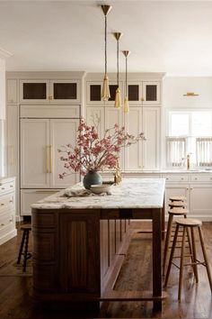 a kitchen with wooden floors and white cabinets, marble counter tops, and bar stools