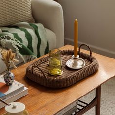 a wicker tray on a coffee table with a candle and tea cup sitting on it