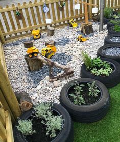 there are many toy trucks in the garden with rocks and gravel on the ground next to each other