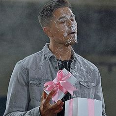 a man holding a gift wrapped in pink and white paper