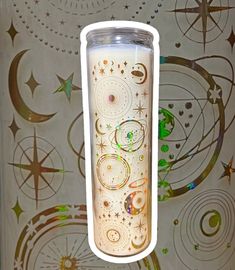 a white candle sitting on top of a table next to a wall covered in stars and circles