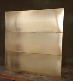 a piece of metal sitting on top of a wooden table next to a wall and floor