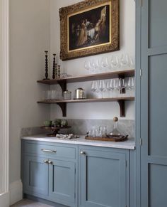 a kitchen with blue cabinets and shelves filled with wine glasses