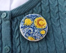 a blue sweater with a yellow and white button on it that has the starry night