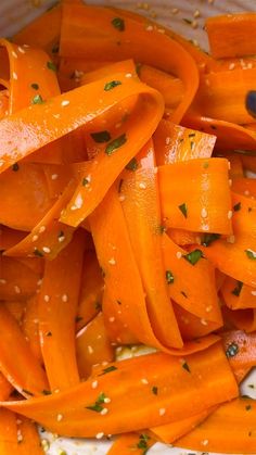 sliced carrots in a white bowl with seasoning on the top and sprinkles