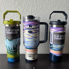 three travel mugs sitting next to each other on a table