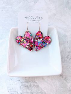 These gorgeous acrylic chunky glitter heart earrings are a must have! They are extremely lightweight and hooks are gold-plated stainless steel or stainless steel, use the pull down tab to choose your hook color. They measure 2.75 in., which includes the length of the hook. Choose from purple chunky glitter or multi-colored neon pink chunky glitter. Be sure to grab the matching studs for your mini me. Heart Resin Earrings, Fun Heart-shaped Earrings For Valentine's Day, Chandbalis Earrings, Valentine Earrings, Epoxy Jewelry, Heart Resin, Resin Creations, Valentines Earrings, Glitter Acrylic