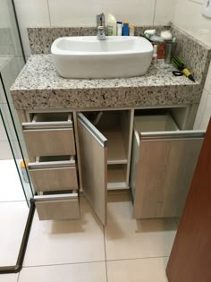 a bathroom sink sitting under a mirror next to a counter top with drawers underneath it