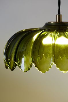 a green glass light hanging from a ceiling