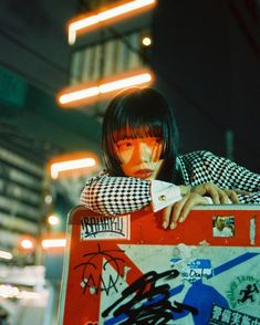 a woman leaning on a red suitcase with graffiti all over it and her hand on the handle