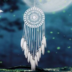 a white dream catcher hanging from the side of a window with stars in the background