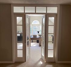 an open door leading to a living room with white walls and carpeted flooring