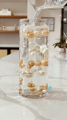 a glass vase filled with water and donuts on top of a marble countertop