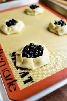 small pastries on a baking sheet with blueberries in the middle, ready to be baked