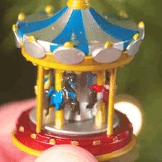 a toy carousel is being held by someone's hand