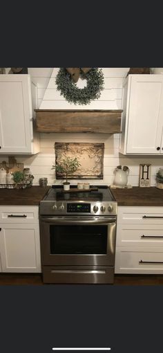 a stove top oven sitting inside of a kitchen next to white cupboards and drawers