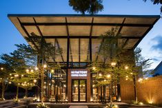 the entrance to an outdoor restaurant with lights on it's sides and trees in front