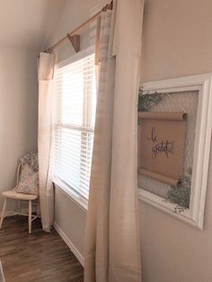 a bedroom with a chair, window and framed sign on the wall in front of it