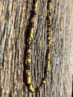 a beaded necklace is hanging from a tree trunk with beads attached to the clasp