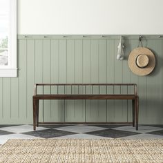 a wooden bench sitting in the middle of a room next to a wall with green paneling