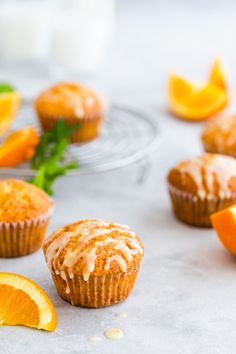 muffins with icing and orange slices on a table