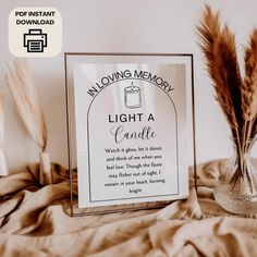 a glass vase filled with brown feathers next to a sign that says moving memory light a candle