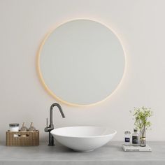 a white sink sitting under a round mirror