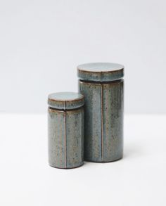 two ceramic containers sitting next to each other on a white surface with no one around them