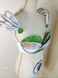 a white mannequin with green and silver decorations on it