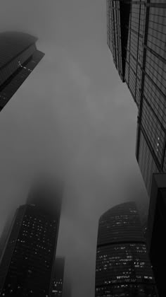 black and white photograph of skyscrapers in the foggy cityscape, looking up into the sky