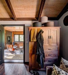 an open closet in the middle of a living room with wooden floors and ceiling beams