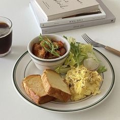 a white plate topped with food next to a cup of coffee and a stack of books