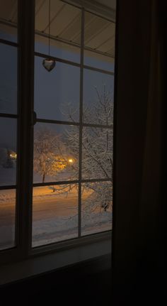 an open window looking out onto a snowy street at night, with the lights on