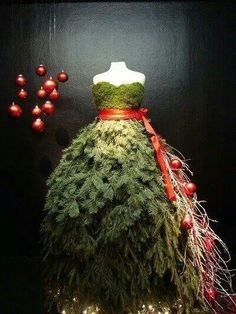 a dress made out of branches with ornaments around it and a red ribbon on the waist