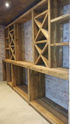 the shelves are made out of wood and have wine racks on them in an unfinished room