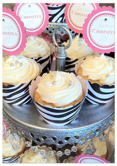 cupcakes with white frosting and black and pink decorations on a silver platter