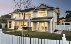 a large white house sitting next to a lush green field at night with the lights on