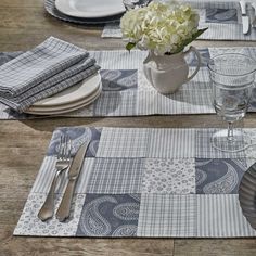 a table set with place mats, silverware and flowers in a vase on the table