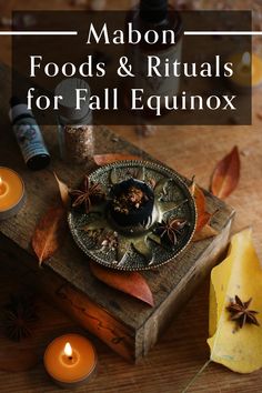 a wooden table topped with candles and an autumn decoration on top of it, surrounded by leaves