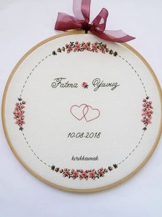 embroidered wedding ornament with two hearts and ribbon on white wall hanging from wooden hoop