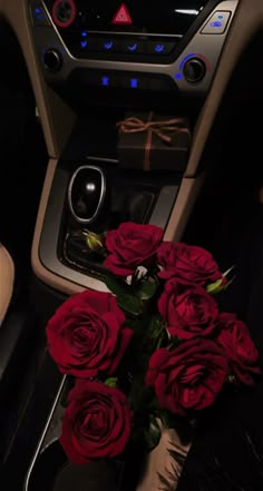 a bunch of red roses sitting on top of a table in front of a car