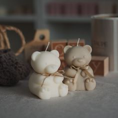 two small white bears sitting next to each other on top of a table in front of a coffee cup