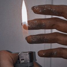 a person holding a lighter in their hand with glitter all over it's fingers